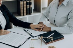 Lawyer providing legal support service to a client during a legal consultation, with documents in the foreground.